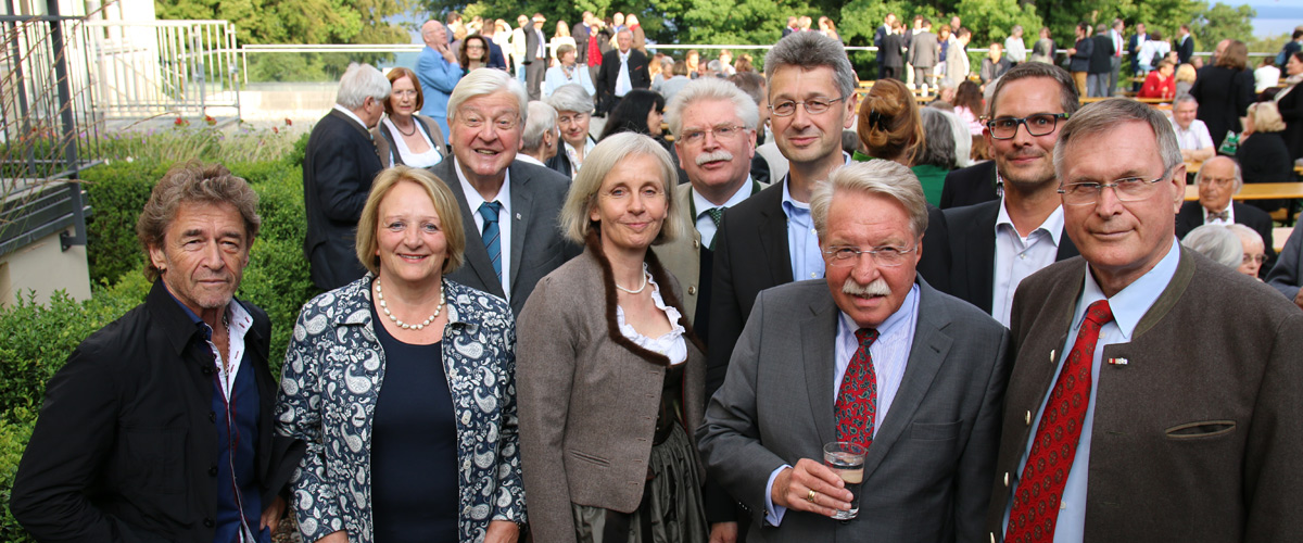 Peter Maffay, Sabine Leutheusser-Schnarrenberger, Hans Maier, Ursula Münch, Martin Zeil, Michael Piazolo, Otmar Bernhard, Andreas Lotte und Johannes Singhammer stehen zusammen im Geraten der Akademie für Politische Bildung und posieren für ein Foto. Im Hintergrund sitzen und stehen weitere Gäste des Gartenfests an Bierbänken