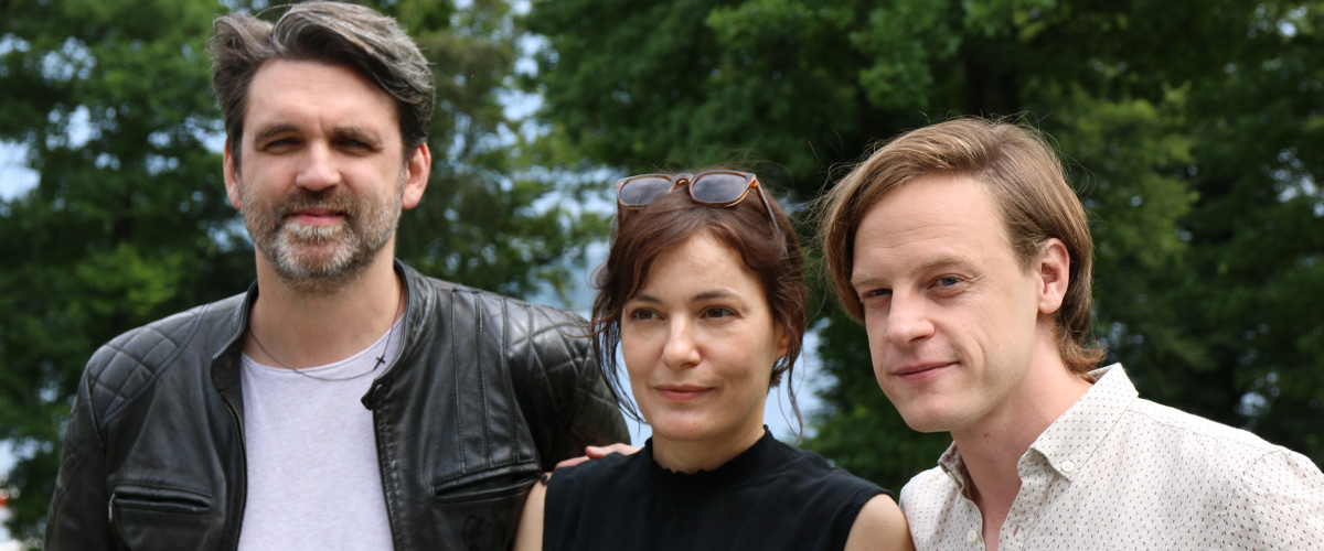 Sebastian Schipper, Nicolette Krebitz und Matthias Koßmehl stehen im Garten der Akademie für Politische Bildung und lächeln in die Kamera