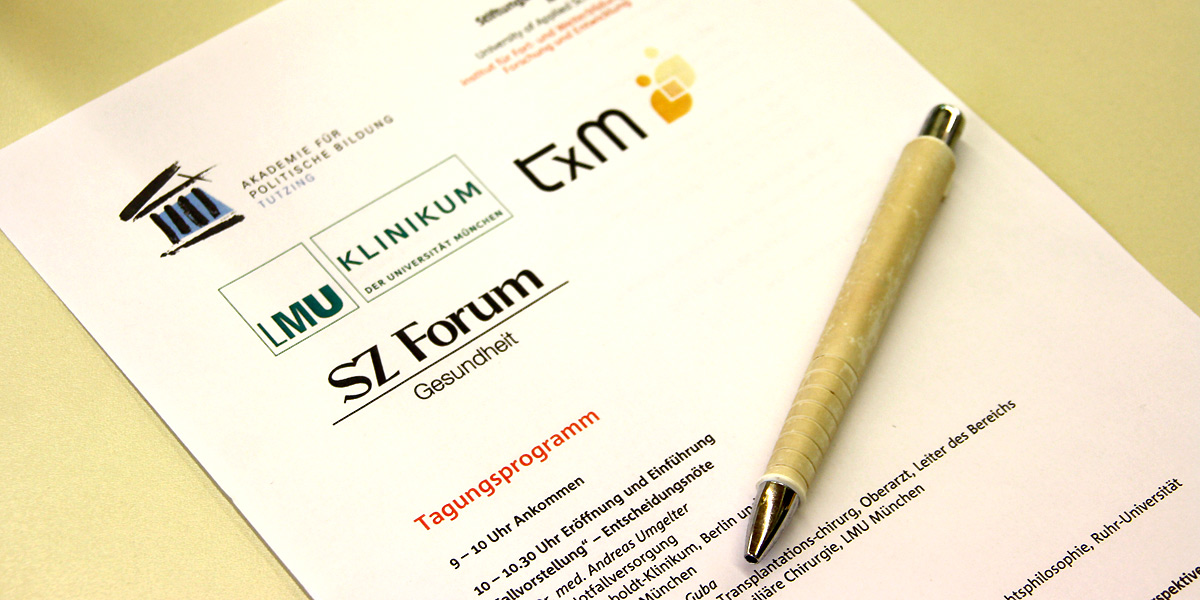 Ein Tagungsprogramm, auf dem ein Kuli liegt, liegt auf einem weißen Tisch