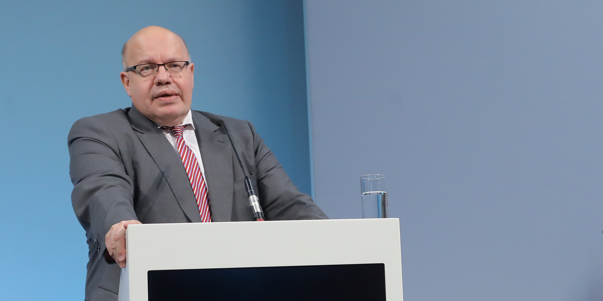 Peter Altmaier steht an einem Rednerpult mit Mikrofon. Rechts von ihm ist ein Glas Wasser