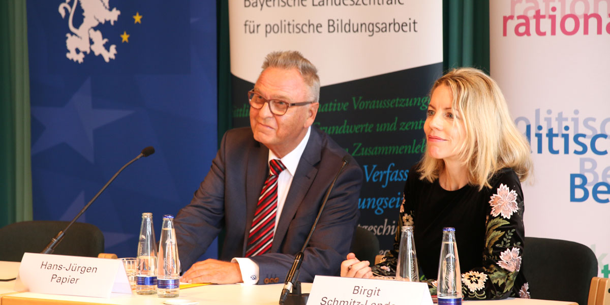 Hans-Jürgen Papier und Birgit Schmitz-Lenders sitzen nebeneinander an zwei Tischen, auf denen jeweils zwei Wasserflaschen und ein Mikrofon stehen