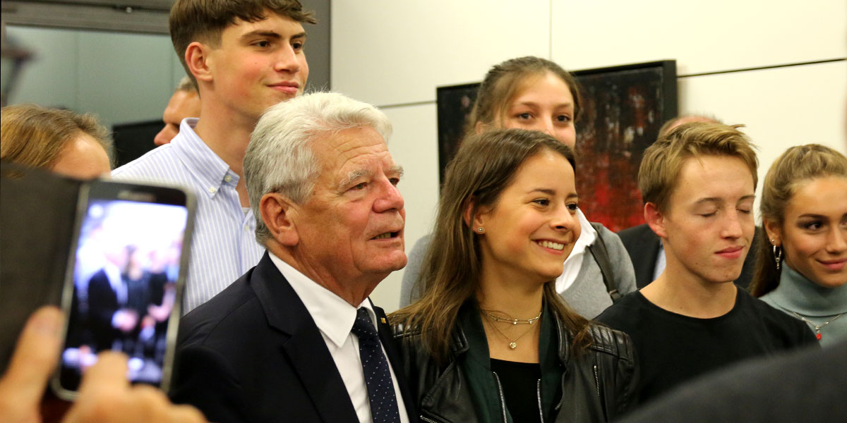 Joachim Gauck steht in der Mitte von jungen Menschen in der Akademie für Politische Bildung Tutzing