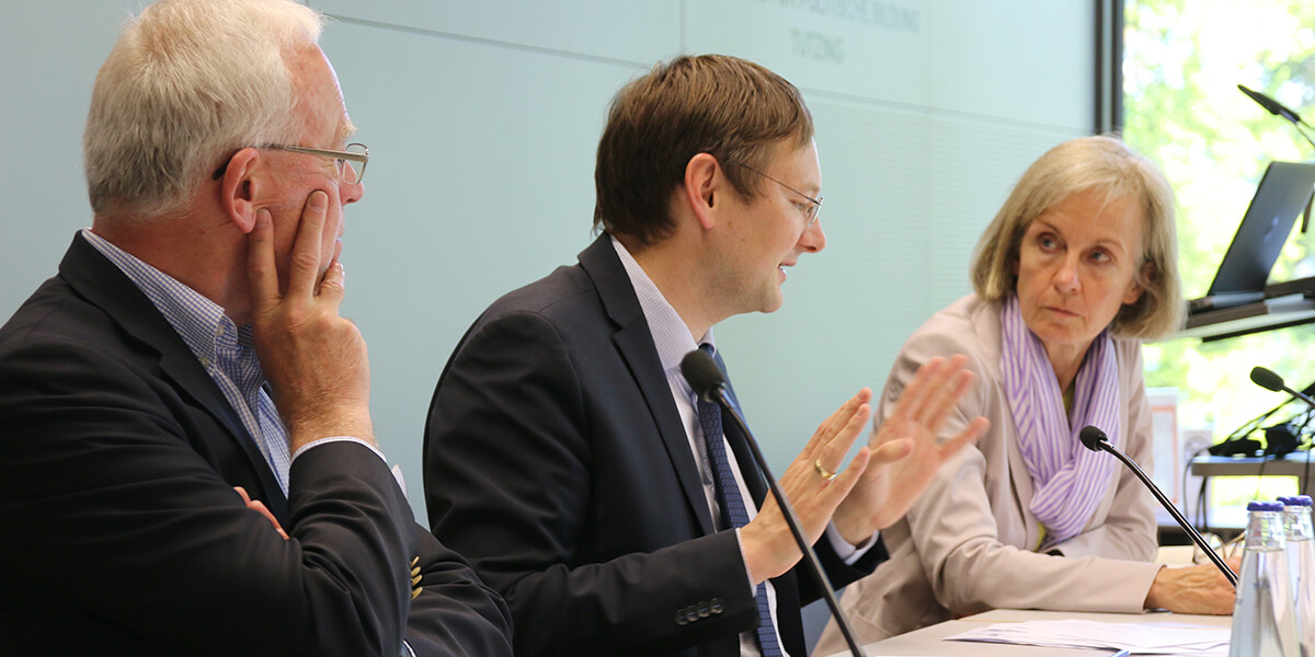 Norbert Gebekken, Hans Reichhart und Ursula Münch sitzen an Tischen auf dem Podium der Akademie für Politische Bildung Tutzing und führen eine Diskussion.