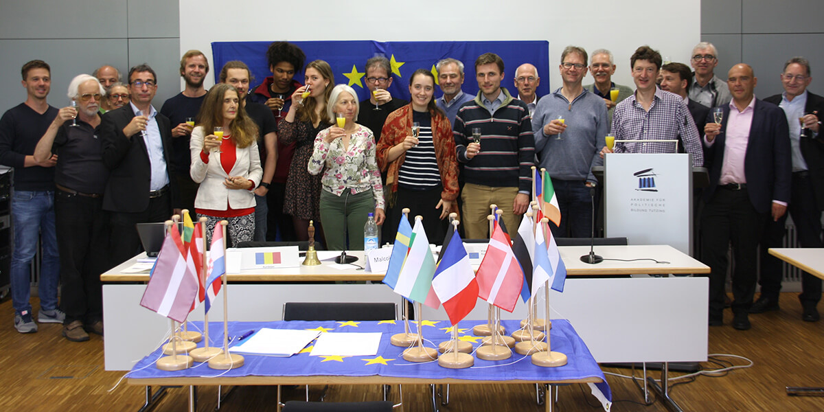 Die Teilnehmerinnen des Planspiels "Brennpunkte europäischer Politik" stehen nebeneinander und posieren für ein Gruppenfoto. Sie halten jeweils ein Glas mit Sekt oder mit Orangensaft in der Hand. Vor ihnen stehen zwei Tische, vor denen noch ein Tisch steht. Auf dem vordersten Tisch liegt eine EU-Flagge und darauf stehen weiter Flaggen von verschiedenen EU-Ländern