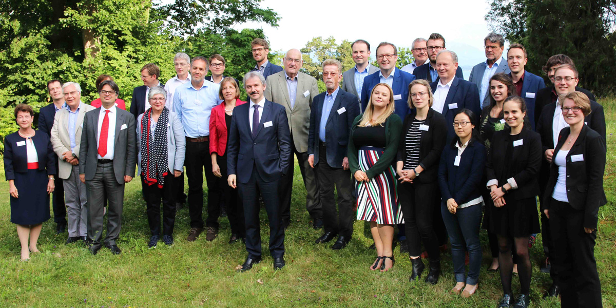 Mehrere Personen stehen im Garten der Akademie für Politische Bildung Tutzing und lächeln in die Kamera