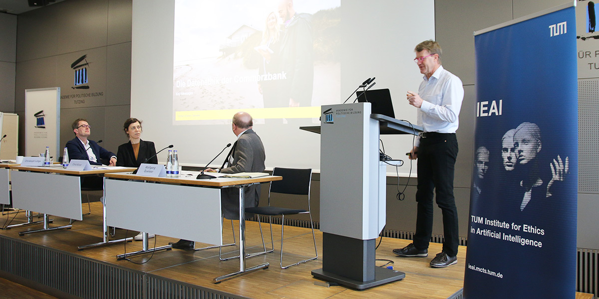 Eberhard Schnebel steht am Rednerpult im Hörsaal der Akademie für Politische Bildung Tutzing. Neben ihm sitzen Christoph Lütge, Chris Köver und Wolfgang Quaisser jeweils an einem Tisch.
