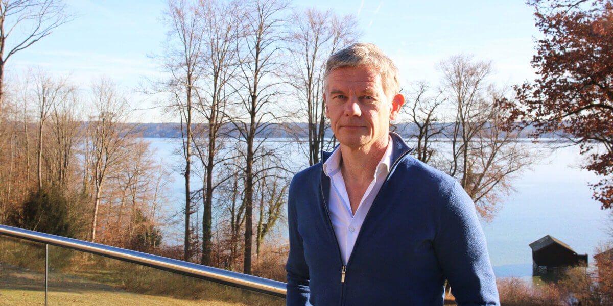 Stephan Malinowski steht im Garten der Akademie für Politische Bildung Tutzing. Im Hintergrund ist der Starnberger See zu sehen.