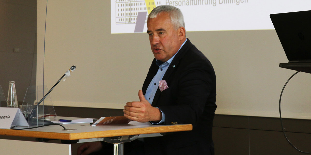 Ludwig Spaenle sitzt an einem Tisch auf der Bühne des Hörsaals der Akademie für Politische Bildung Tutzing und redet in ein Mikrofon