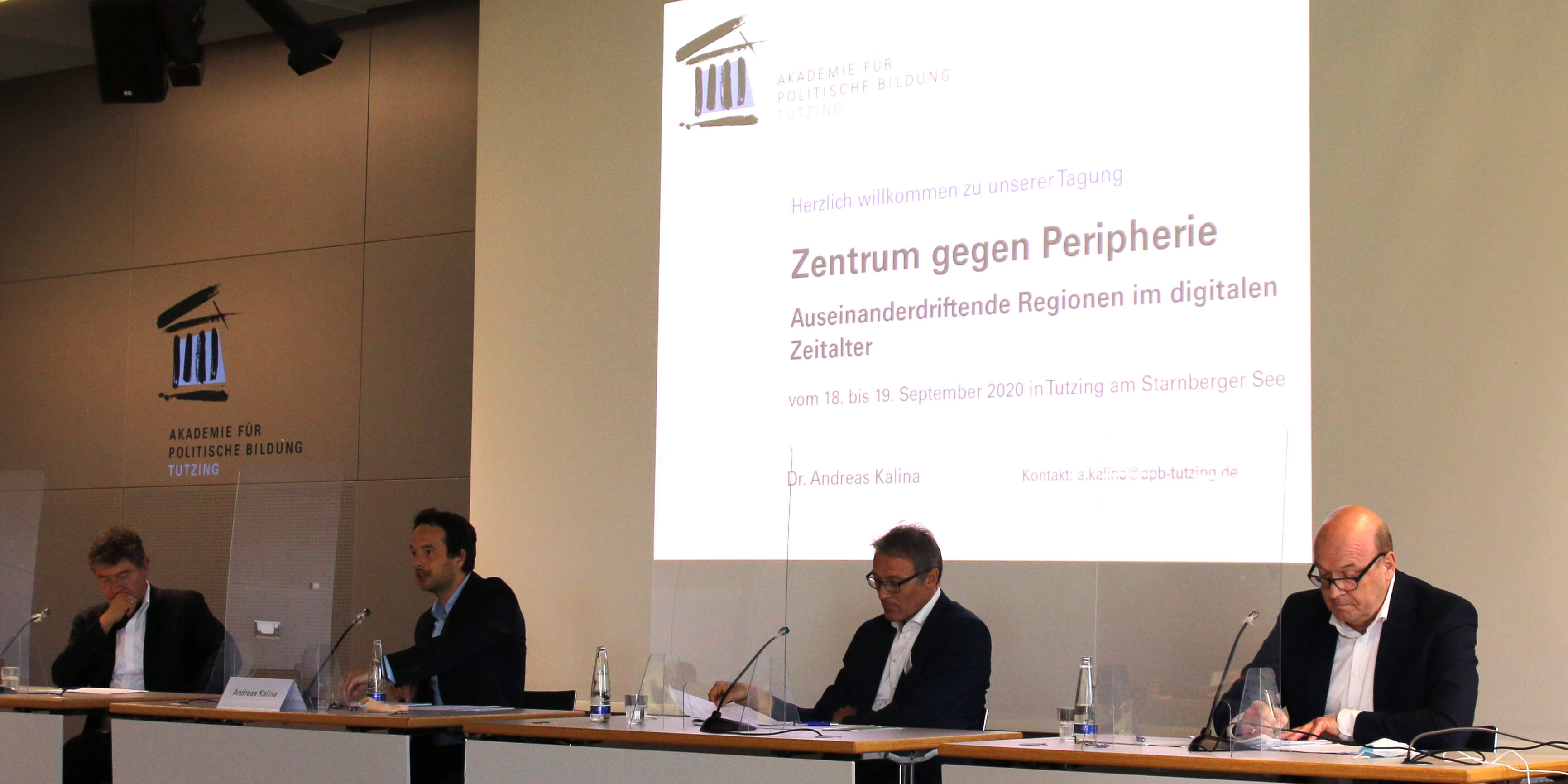 Mark Michaeli, Andreas Kalina, Klaus Ulrich und Hans-Peter Klös sitzen jeweils an einem Tisch mit Mikrofon auf der Bühne des Hörsaals der Akademie für Politische Bildung Tutzing