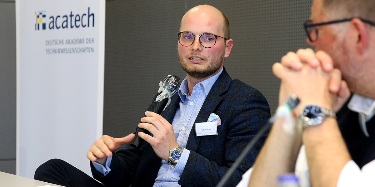 Peter Kraemer von acatech sitzt mit einem Mikrofon in der Hand links, rechts neben ihm sitzt Matthias Brucke von embeteco. Im Hintergrund ist das Logo von acatech zu sehen.