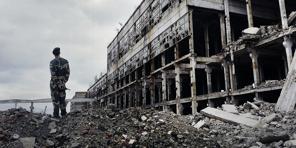 Soldat neben einem ausgebombten Gebäude
