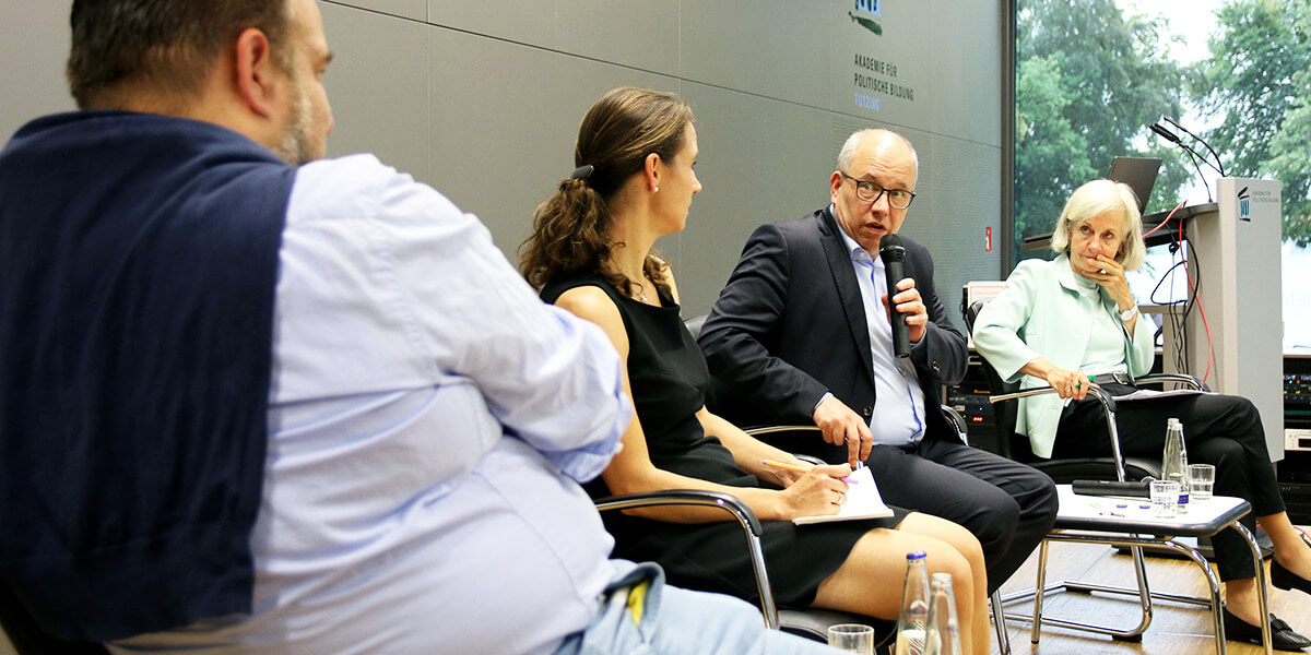 Alexander Handschuh sitzt bei einer Podiumsdiskussion in der Akademie für Politische Bildung und spricht in ein Mikrofon. Um ihn herum sitzen Ursula Münch, Franziska Armbruster und Malte Spitz und wenden sich ihm zu.