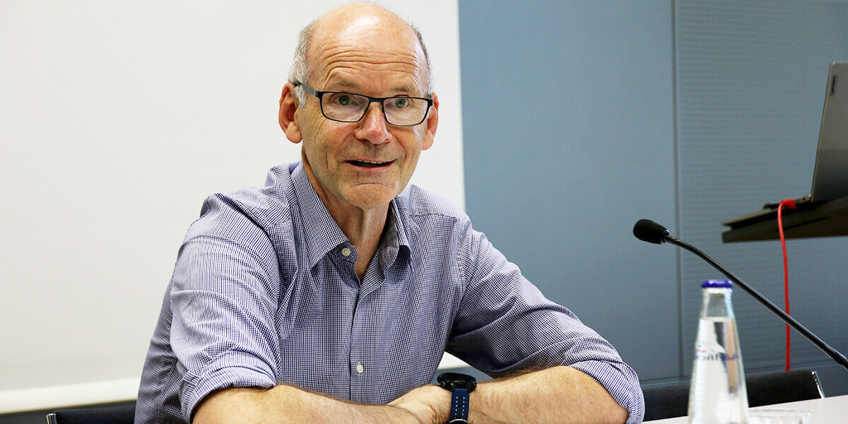 Ulrich Walwei sitzt mit verschränkten Armen auf dem Podium der Akademie für Politische Bildung und spricht in ein Mikrofon.
