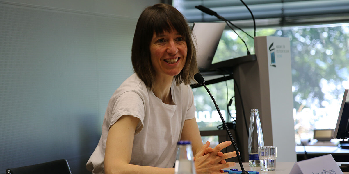 Agnes Blome sitzt auf dem Podium der Akademie für Politische Bildung und spricht.