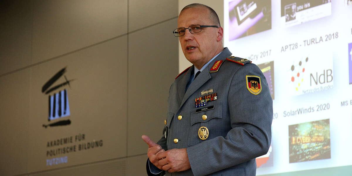 Brigadegeneral Rainer Simon steht auf dem Podium der Akademie für Politische Bildung und hält seinen Vortrag.