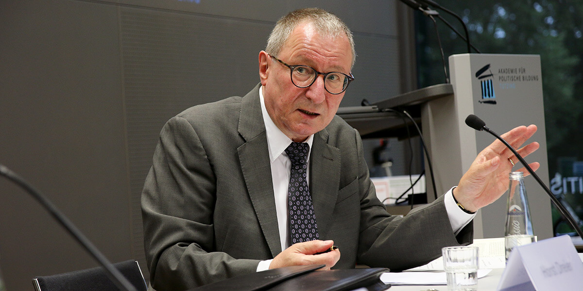 Horst Dreier sitzt auf dem Podium an der Akademie für Politische Bildung und spricht in ein Mikrofon.