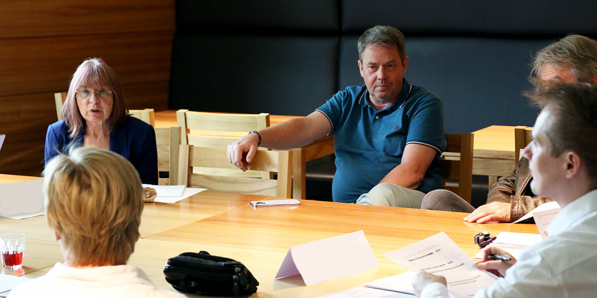 Eine Gruppe von Menschen sitzt um einen Tisch und unterhält sich.