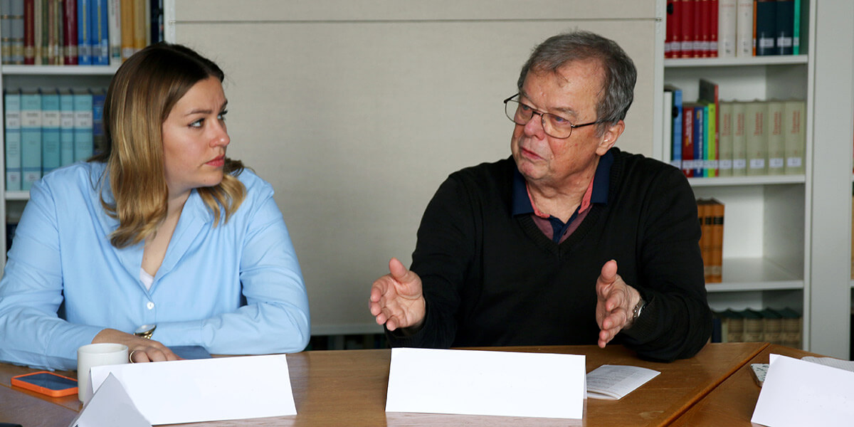 Eine Teilnehmerin und ein Teilnehmer der Tagung "Mein Beitrag zur Energiewende" sitzen im Workshop, vor einem Tisch und unterhalten sich.