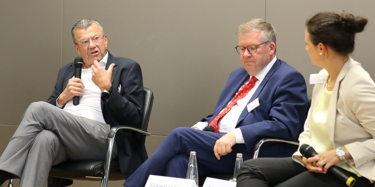 Christoph Leicher sitzt auf dem Podium der Akademie für Politische Bildung und spricht mit einem Mikrofon zu Giulia Mennillo. Zwischen den beiden sitzt Volkmar Halbleib.