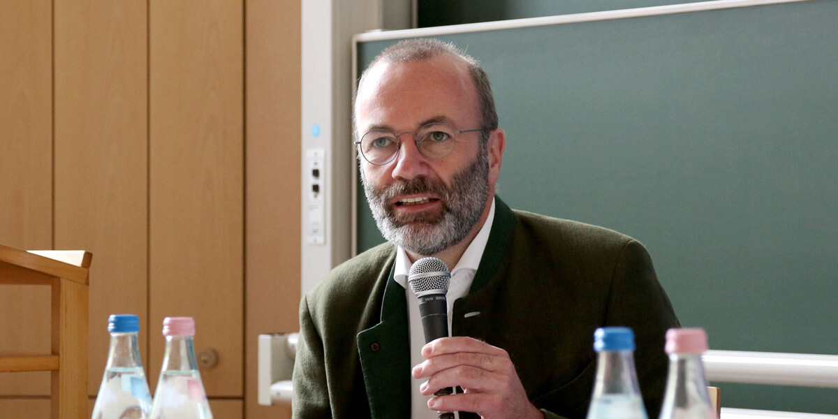 Manfred Weber sitzt vor einer Tafel und spricht in ein Mikrofon.