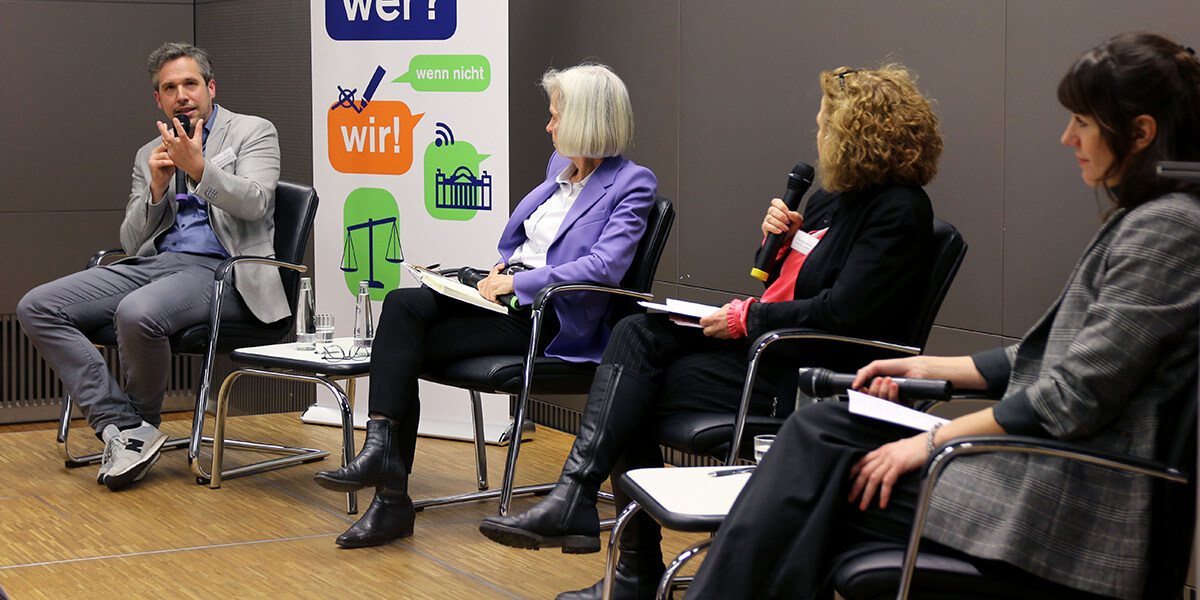 Claus Oberhauser sitzt auf dem Podium der Akademie für Politische Bildung und spricht in ein Mikrofon. Rechts von ihm sitzen Ursula Münch, Daniela Arnu und Nicole Harth und wenden sich ihm zu.