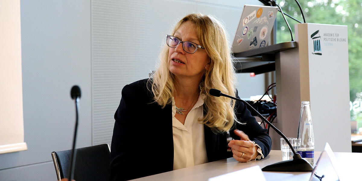 Natali Helberger sitzt auf dem Podium der Akademie, blickt nach links und spricht in ein Mikrofon.