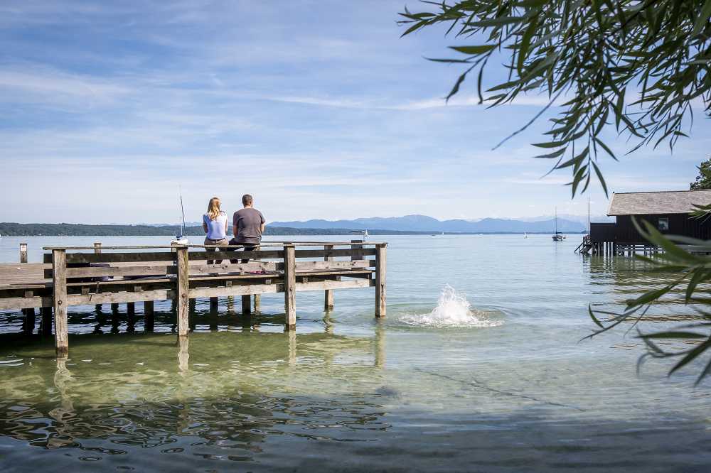 Zwei Personen sitzen auf dem Badesteg der Akademie für Politische Bildung