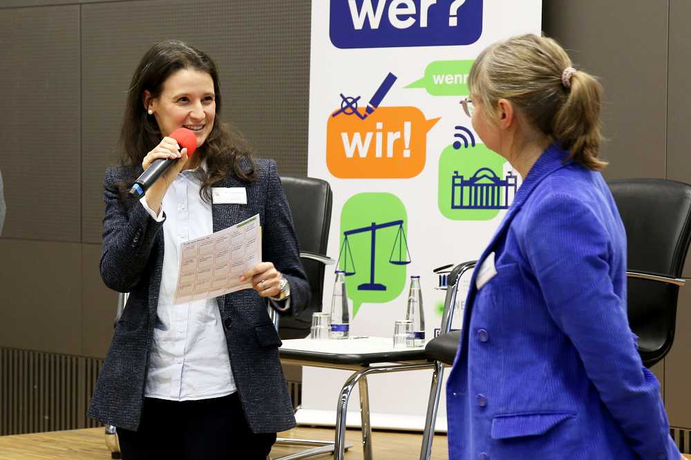Giulia Mennillo spricht im Auditorium der Akademie für Politische Bildung in ein Mikrofon. Neben ihr steht Silke Zimmermann und hört zu.
